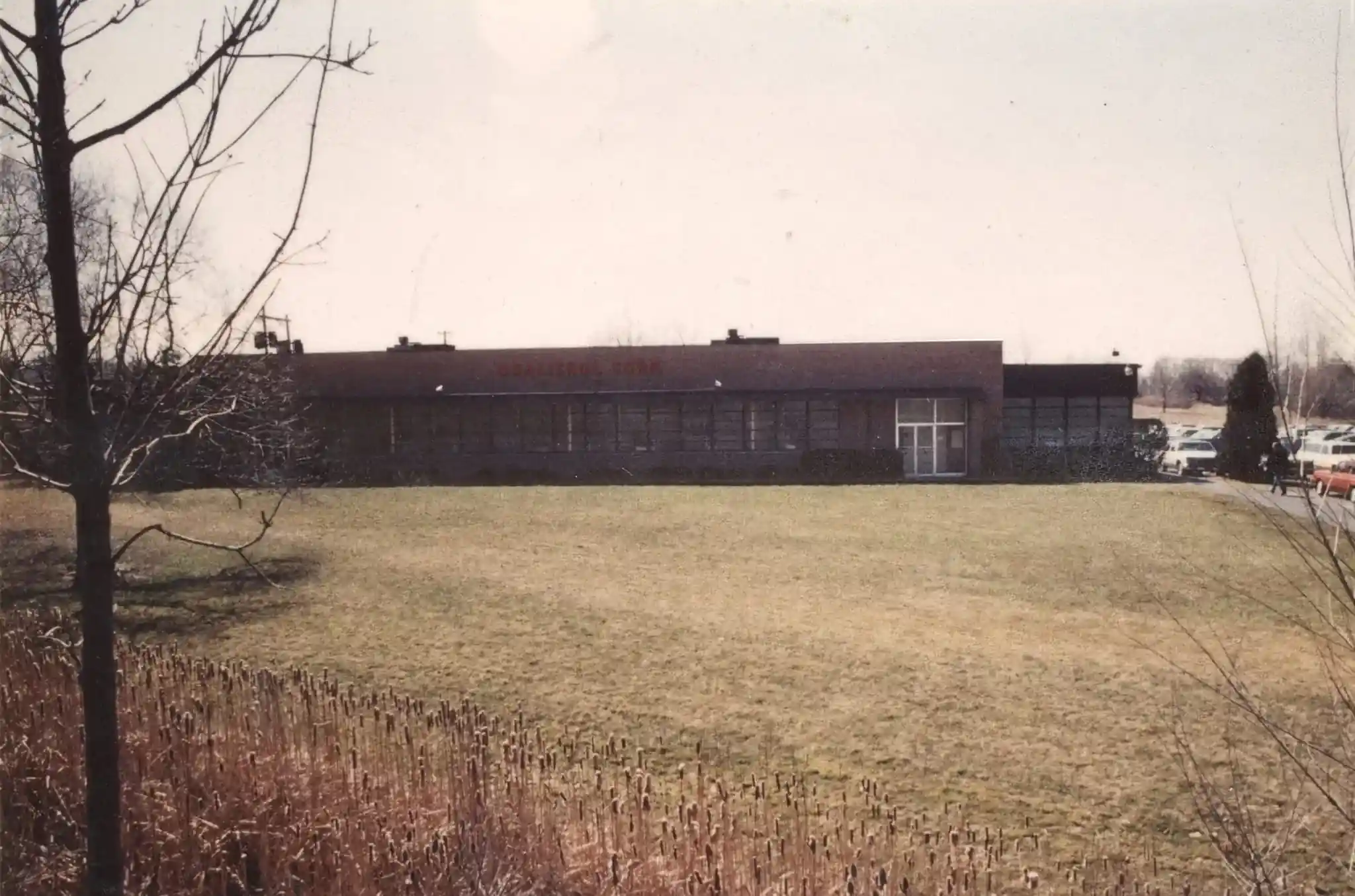 Vintage black and white photograph of Qualitrol factory building with electrical transmission infrastructure
